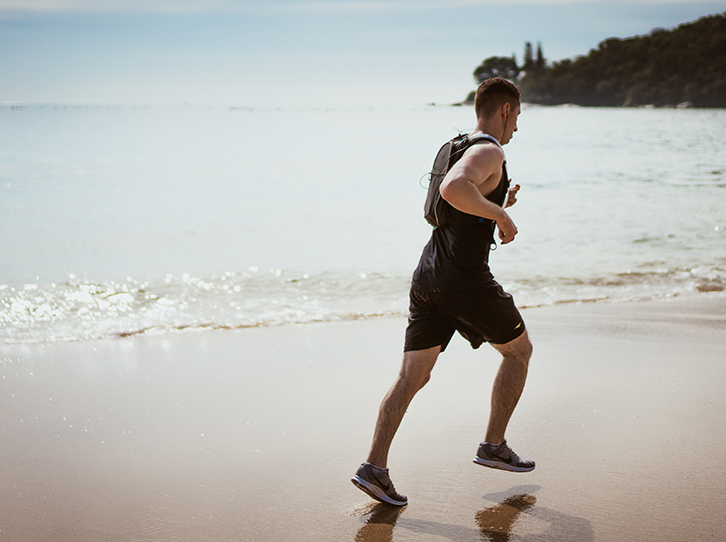 Man running on beach with runners knee